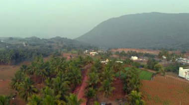 Yeşil ve uzak tepelerle çevrili sakin bir kırsal köy, gün doğumunda dingin güzellikleri sergiliyor..