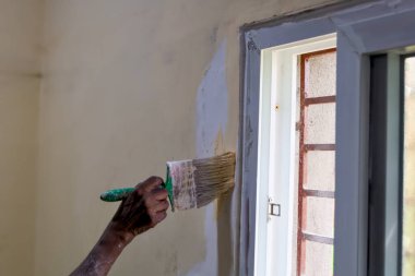 İyi ışıklandırılmış bir iç mekanda ev dekorasyonu sırasında pencere çerçevesine boya sürmek.