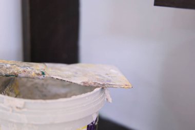 Renk ve yaratıcılıkla dolu bir sanatçının çalışma alanıyla çevrili bir boya kutusunun kenarında palet bıçağı duruyor..