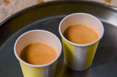 Sıradan bir toplantı sırasında parlak metal bir tepside iki fincan kokulu çay sunulur..