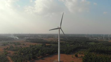 Geniş bir kırsal alanda bulutlu bir gökyüzünün altında büyük bir rüzgar türbini temiz enerji üretir..