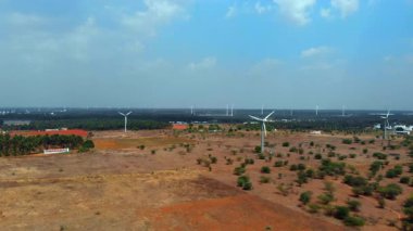 Rüzgâr türbinleri, kuru kırsal bir alanda, mavi gökyüzü altında temiz enerji üretimine katkıda bulunarak, dik dururlar..