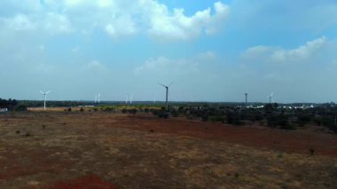 Rüzgar türbinleri uçsuz bucaksız bir arazide mavi gökyüzünün altında yenilenebilir enerjiyi sembolize eder..