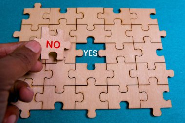 Bir el, ahşap bir yapbozun içine 'Hayır' yazan bir parça yerleştirir. Bu an karar vermeyi ve tercihleri simgeliyor..