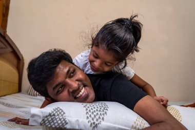 Bir baba ve kızı, sıcak bir evde birlikte gülüp eğlenerek yatakta oynaşmaktan hoşlanırlar..