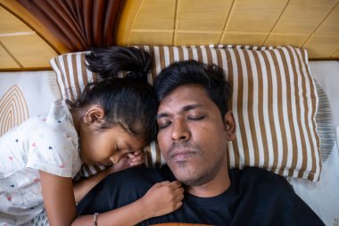 Bir baba ve küçük kızı sıcak bir yatakta birlikte uyur, sevgi dolu bir bağ sergilerler..