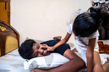 Çocuk, babasıyla oyun oynayarak, rahat bir ortamda yatarak neşeli aile anıları yaratıyor..