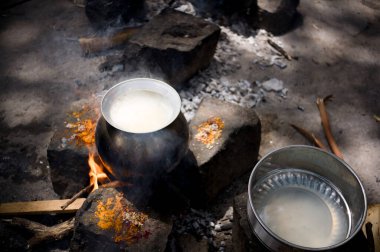Baharatlar etrafını sararken siyah bir tencere açık alevin üzerinde kaynıyor ve dışarıda kırsal bir yemek atmosferi yaratıyor..