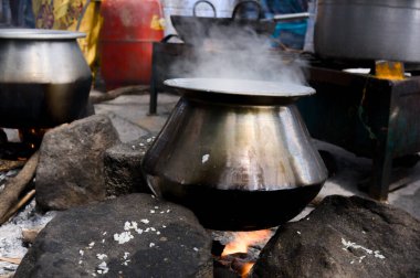 Taşların üzerine yerleştirilmiş büyük bir tencereden buhar yükseliyor, açık bir ateş üzerinde geleneksel yemekleri pişiriyor..