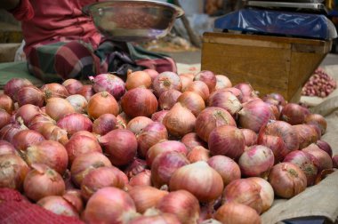 Tedarikçiler, güneşli bir günde hareketli bir markette taze, canlı soğanlar sergileyerek yakınlardaki müşterileri cezbediyor..