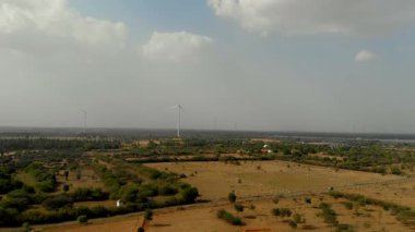 Bulutlu bir gökyüzünün altında rüzgâr türbinleriyle geniş bir alan.