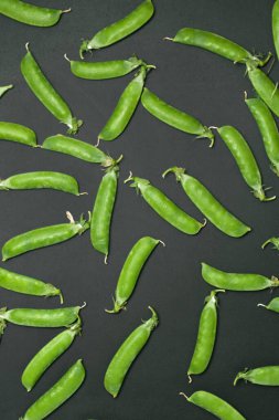 Siyah arka planda kabuklu taze bezelyeler..