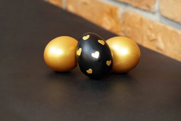 Gold, black and white Easter eggs on a dark gray background