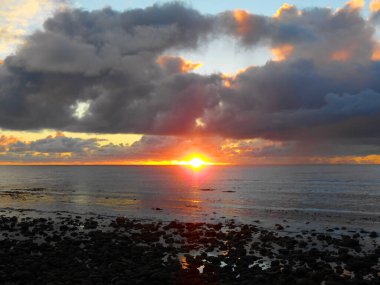 Deniz kıyısında bulutlu bir gün batımı