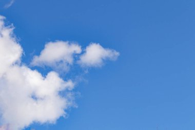 Pofuduk beyaz bulutlu parlak mavi gökyüzü. Güneş ışığıyla aydınlatılan yumuşak bulut şekilli doğal bir arka plan. Hava, doğa ve manzara temaları için mükemmel