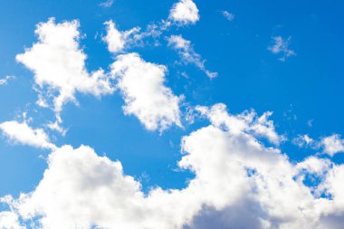 Pofuduk beyaz bulutlu parlak mavi gökyüzü. Güneş ışığıyla aydınlatılan yumuşak bulut şekilli doğal bir arka plan. Hava, doğa ve manzara temaları için mükemmel