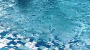 Açık mavi yüzme havuzu ve su yüzeyinde güneş ışığı yansımaları. Sakin dalgalar rahatlatıcı yaz havası yaratır, arka plan, seyahat ve tatil kavramları için mükemmeldir..