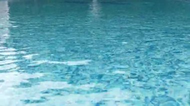 Açık mavi yüzme havuzu ve su yüzeyinde güneş ışığı yansımaları. Sakin dalgalar rahatlatıcı yaz havası yaratır, arka plan, seyahat ve tatil kavramları için mükemmeldir..