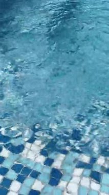 Açık mavi yüzme havuzu ve su yüzeyinde güneş ışığı yansımaları. Sakin dalgalar rahatlatıcı yaz havası yaratır, arka plan, seyahat ve tatil kavramları için mükemmeldir..