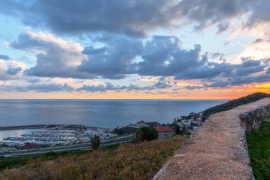 Bir liman ve gemileri gösteren bir uçurumdan okyanus manzarası.