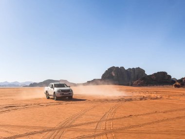 Beyaz 4x4 Offroad aracı çölün ortasında sürükleniyor ve hareket ediyor.