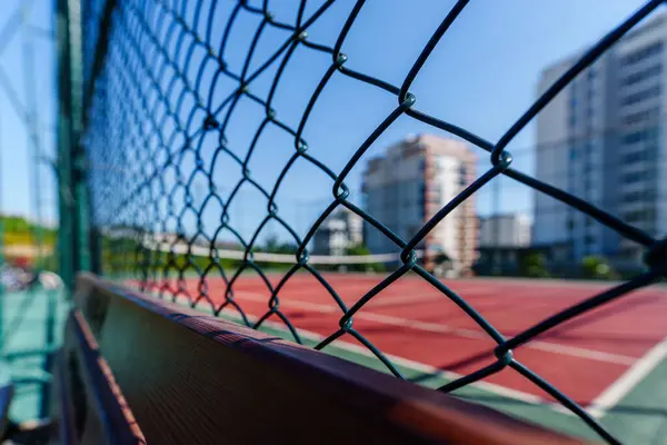 Açık tenis kortunun demirden kilidi olan bir tel örgü.