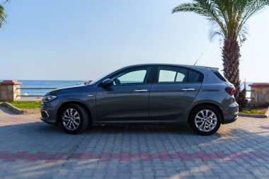 Sahilde mavi gökyüzü ve deniz dalgalarıyla park etmiş bir arabanın inanılmaz görüntüsü.