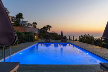 Gün batımında engin okyanus ve denizin üzerinde mavi yüzme havuzu