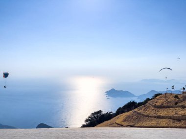 Aydınlık bir günde çarpıcı bir dağ manzarası üzerinde heyecan verici bir uçuşun keyfini çıkaran bir paraglider, macera ve özgürlük sergiliyor..