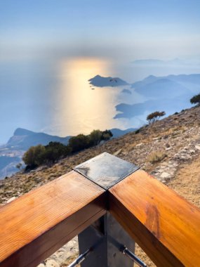 Gün batımında deniz ve dağların dramatik manzarası ve uzaktan bir paraglider. Huzuru, doğayı ve macerayı yakalar.