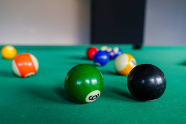 A close-up shot of a pool table highlighting an eight ball in focus. Shows the game setup with colored balls waiting for play. clipart