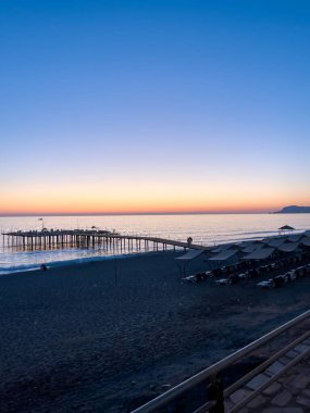 Sakin bir günbatımı, sakin bir okyanus ve iskelenin yer aldığı sakin bir plajın üzerinde pastel renkler bırakır. Sessiz ortam deniz kenarında bir huzur ve rahatlama hissi yaratıyor..