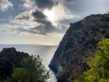Uçurumun tepesinde antik kalıntıları olan engebeli bir kıyı şeridi dramatik bulutlu bir gökyüzü tarafından çerçevelenmiş nefes kesici bir manzara..