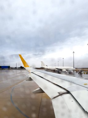 View From an Airplane Window Overlooking a Rainy Airport Apron clipart