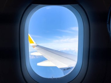 View of the airplane wing and distant skies through a passenger window, evoking travel-related themes of adventure, exploration, and serenity. clipart