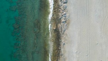 Deniz ve küçük bir teknesi olan kumlu bir sahil manzarası..