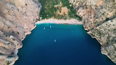 Küçük bir kumsalın, çapalı ve hareket eden tekneli hava aracı görüntüleri.