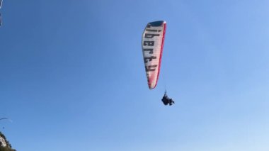Mavi gökyüzünde uçan paraglider