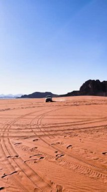 Bir off-road 4x4 kamyonu sıcak bir çölün ortasında kumda sürükleniyor.