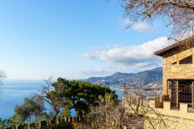 Güzel bir kıyı manzarası. Parlak mavi gökyüzünün altında, yemyeşil bir deniz manzaralı, büyüleyici bir taş ev..