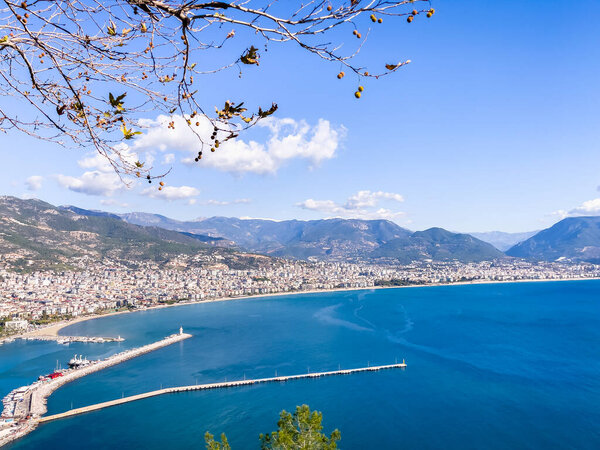A scenic coastal city featuring a vibrant harbor, surrounding mountains, and clear blue skies. Ideal for travel inspirations and showcasing Mediterranean vibes.