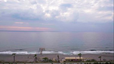 Sakin, yüksek açılı, ağır çekimde, soğuk bir kış gününde manzaralı bir kumsalı çekerken, mavi saat boyunca mor ve renk tonlarını gösteriyordu.