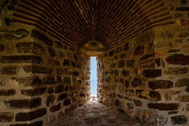 Dar geçitli, iyi yıpranmış taş bir duvar mavi denizlerin manzarasını sağlıyor.