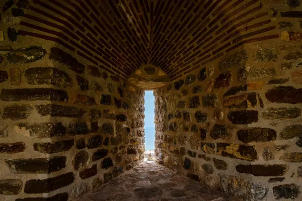 Dar geçitli, iyi yıpranmış taş bir duvar mavi denizlerin manzarasını sağlıyor.