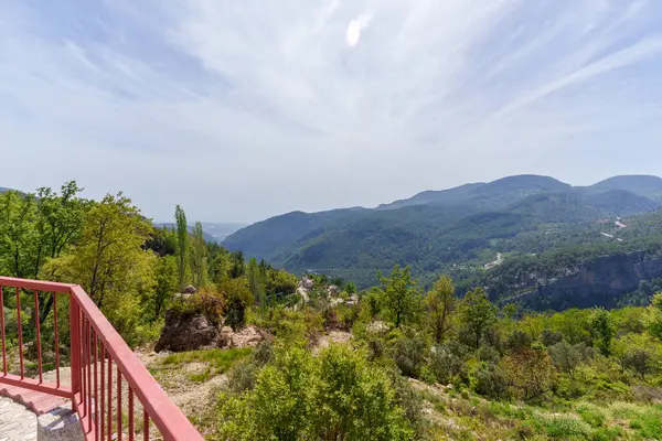 Yeşillik, kırmızı çit ve çarpıcı manzarası olan yüksek bahçe alanı.