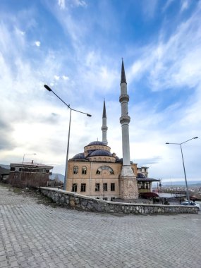 Kubbesi ve bulutlu gökyüzünün altında iki uzun minaresi olan güzel bir cami.