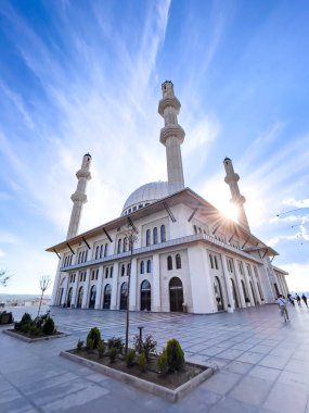Parlak mavi gökyüzünün altında güneşle aydınlatılmış görkemli bir cami.