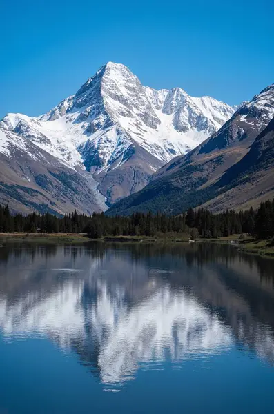 Güzel mavi gökyüzü ve arka planda dağlar olan bir gölün dikey görüntüsü.