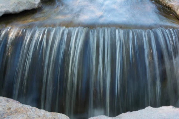 这张照片描绘了一条流经水面的小河 这张照片是在长时间曝光的情况下拍摄的 因此水的颜色很模糊 底部只能看到几块石头 — 图库照片