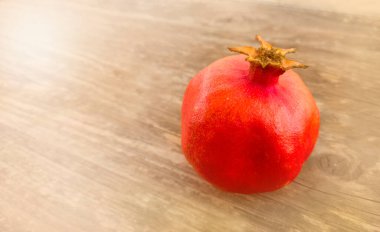 Ahşap bir yüzey ışığının arka planında kırmızı bir nar parlar. Rosh Hashanah bayramının sembolü. Shana tova tebrik kartı ve Yom Kippur için uygun. Metin için boş alanı olan